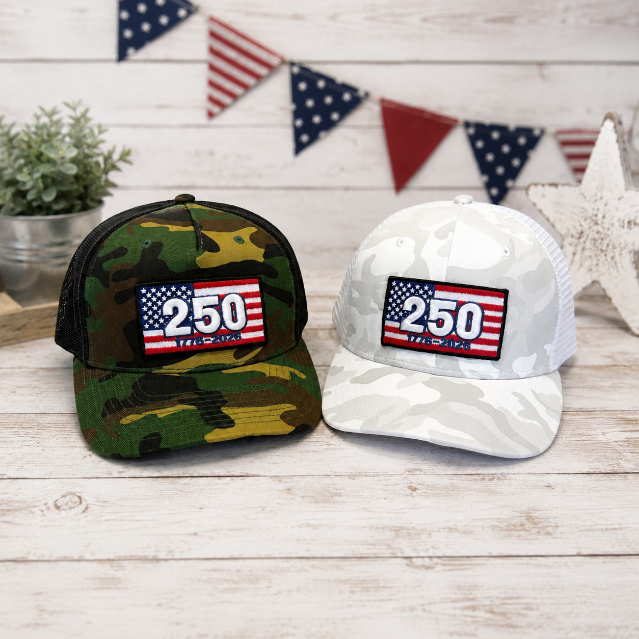 Two hats, one camouflage and one white, with a '250' patch on a wooden surface with American flags in the background.