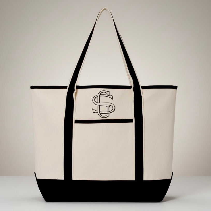 Beige tote bag with black accents and a logo on a light gray background