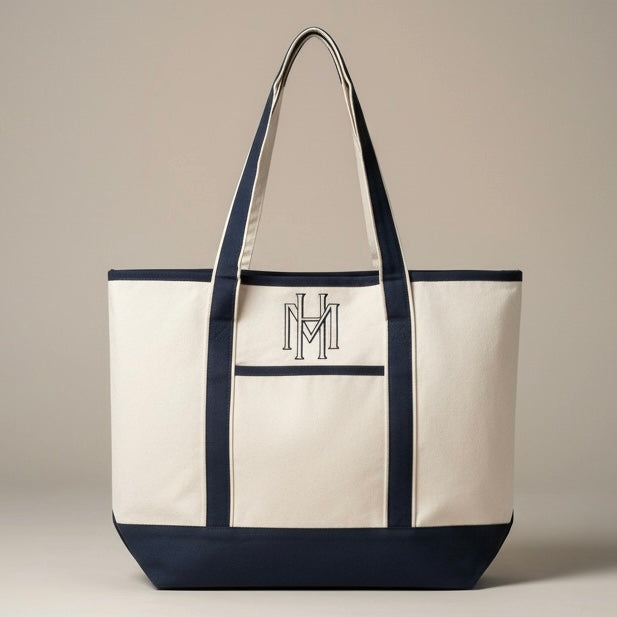 White tote bag with navy accents and a monogram on a beige background