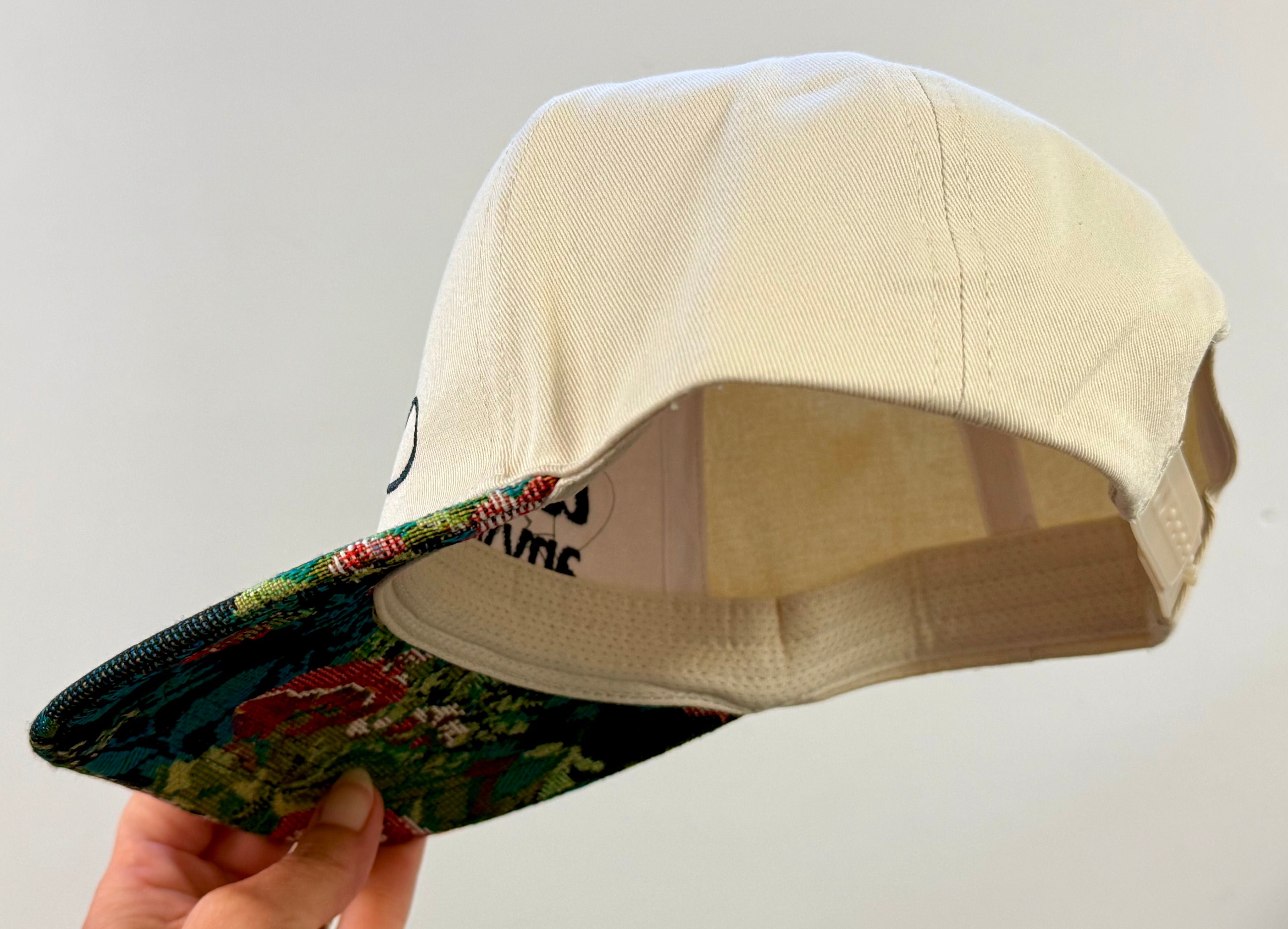 Beige cap with colorful interior being held against a plain background